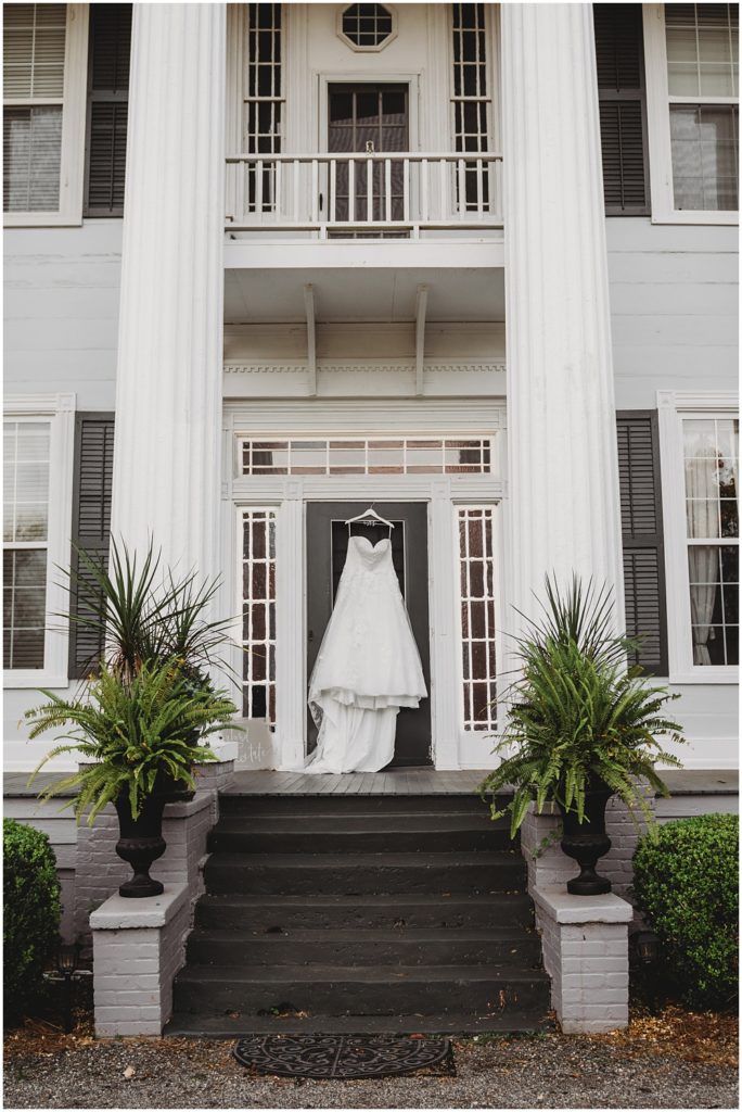 Bride's wedding dress hanging on the door of the front porch at Englund Estate Venue in Georgia 