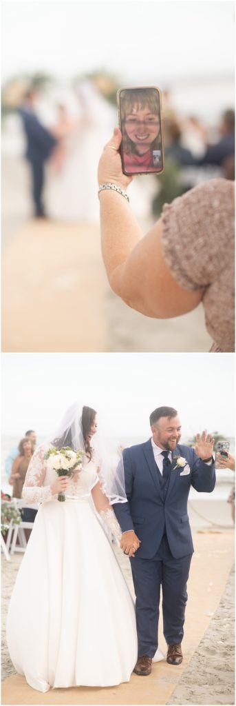 bride and groom walk down the aisle waving at guests. Another guests holds up a cell phone while a guest is on facetime 