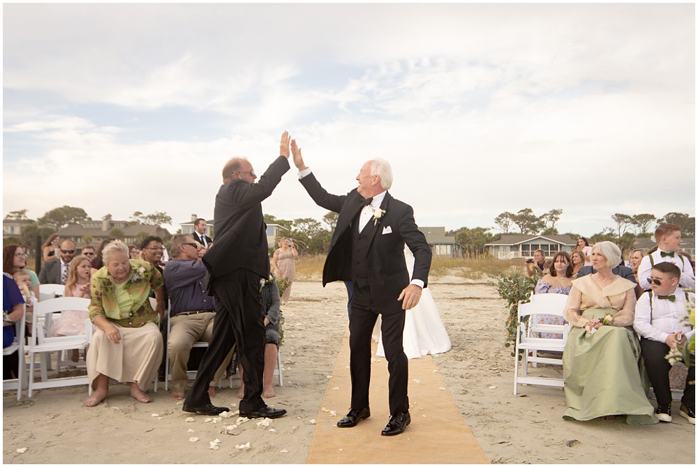 Bride and Groom's dads high five each other at the end of the wedding ceremony