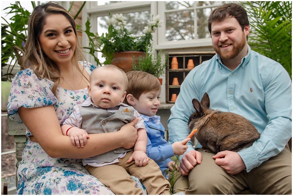 family poses for easter mini session in the greenhouse with Archie the bunny at prospect farms in Lawrenceville, Ga