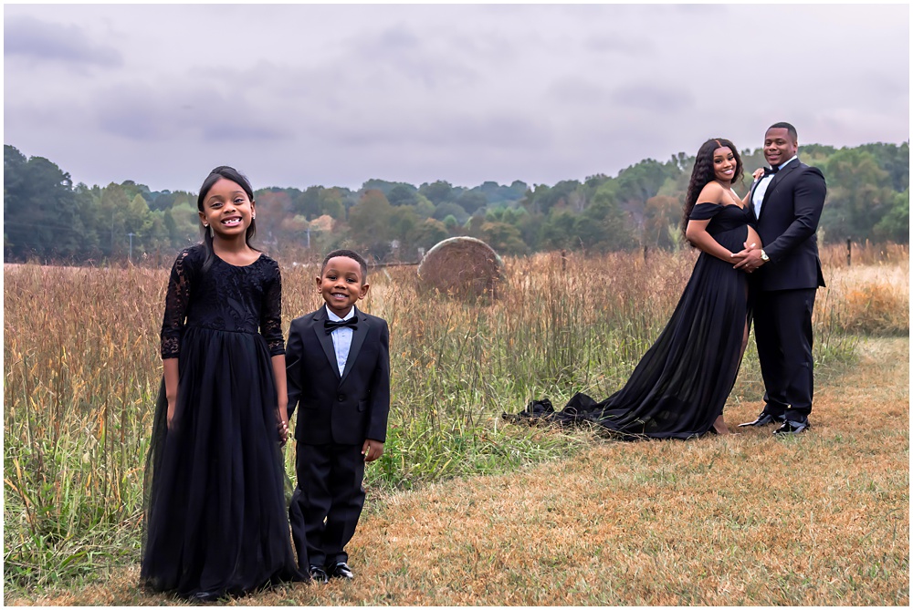 maternity session at Prospect Farms, in Lawrenceville Georgia. Mom and dad are outside in tall grass wearing a long sleeve purple dress and a suit. 