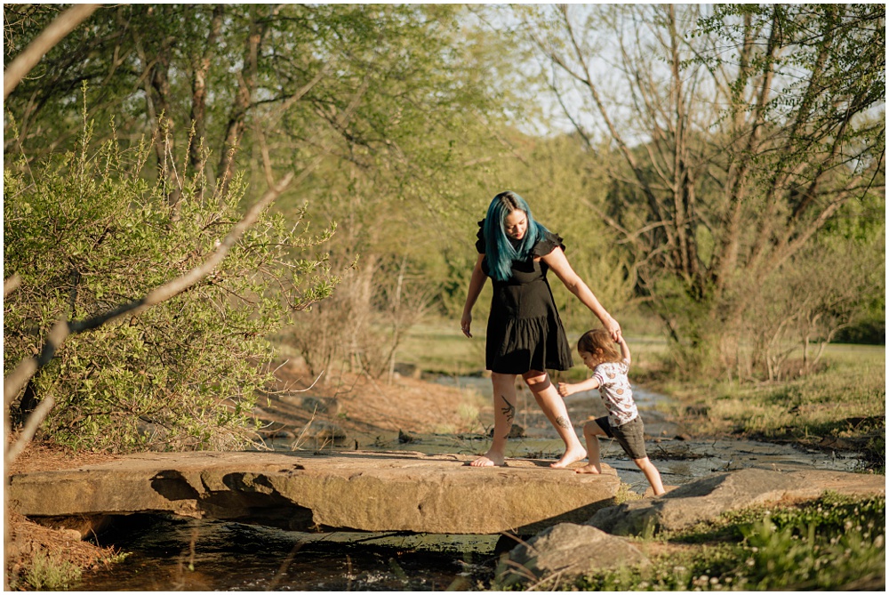 mom helps toddler walk across creek during a mommy and me mini session at gerrard landing park 