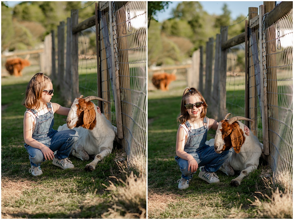 Flowery Branch photographer hosts mini session of little girl playing with baby goats. She's kneeling down petting goats at Prospect Farms, Lawrenceville Ga