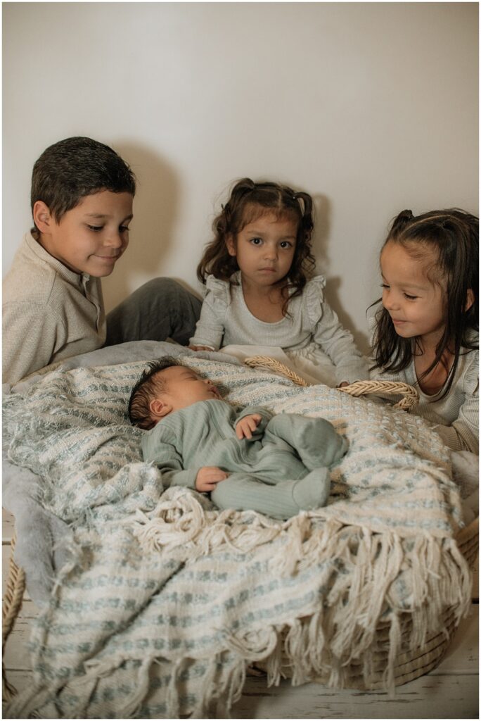 Flowery Branch photographer has a newborn baby in the studio. The newborn is surrounded by his siblings.