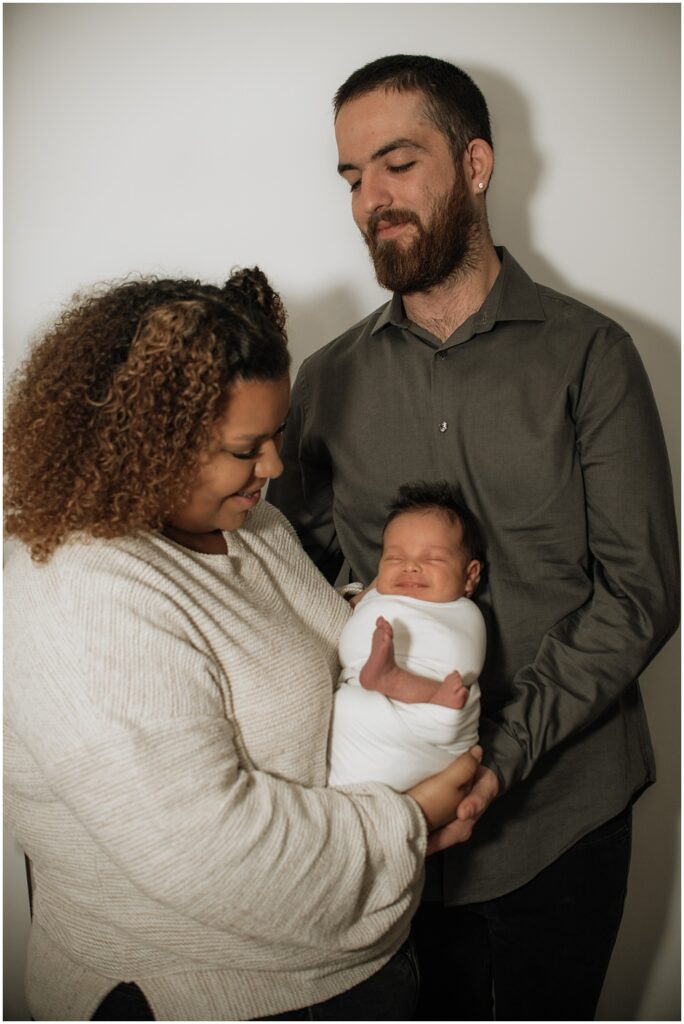 Flowery Branch photographer takes a group photo of the baby and his parents during the newborn session in the studio. Everyone is all smiles.