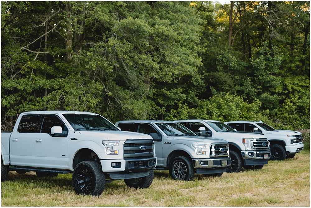 North Georgia photographer photographs a wedding in the country for a young couple in the north Georgia mountains. Photographed here is a row of trucks parked in the grass. 